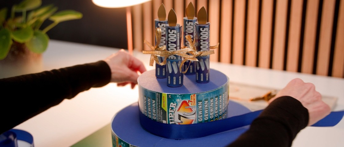 Zwei Hände umwickeln DIY-Torte mit einem Satinband | WestLotto-Rubbellos