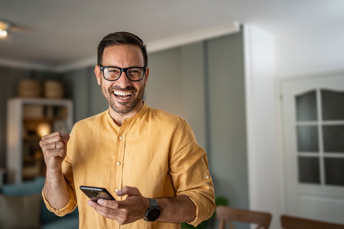 Mann hält Handy in der Hand und jubelt | Eurojackpot-Gewinner NRW