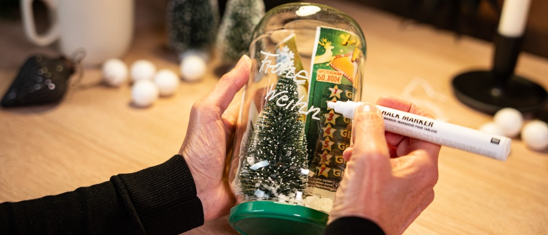 Ein weihnachtlich dekoriertes Gurkenglas wird beschriftet | WestLotto Bastelidee