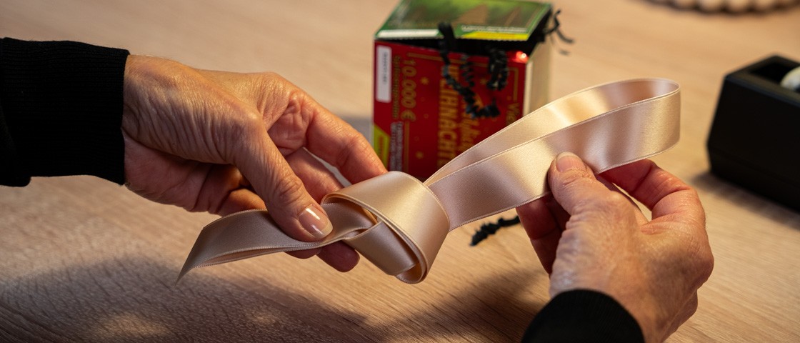 Ein cremefarbenes Schleifenband wird verknotet | WestLotto Bastelidee